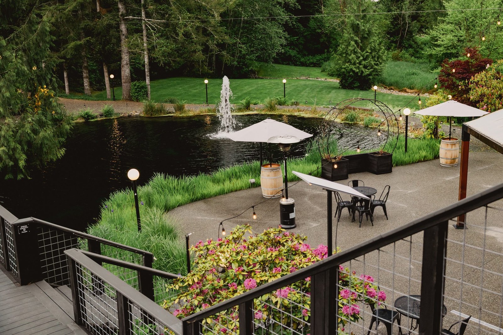 Aerial view of Fox Hollow Farm wedding venue with a pond and fountain, patio umbrellas and garden lawns surrounded by trees