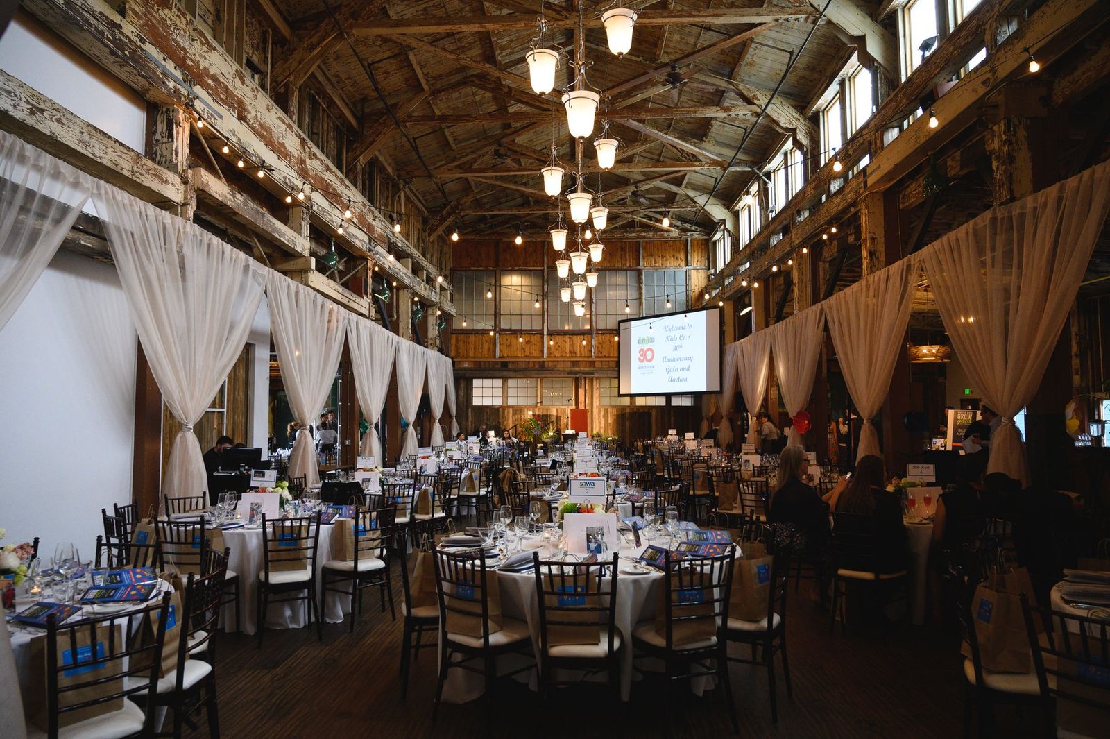 Long tables set for a large corporate event dinner inside SoDo, a timber hall event venue