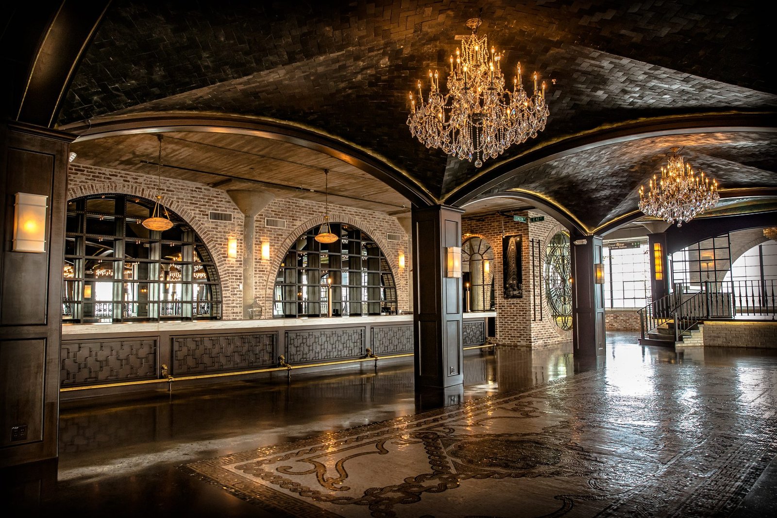 Empty ballroom at The Astorian with crystal chandeliers, arched windows and a patterned marble floor
